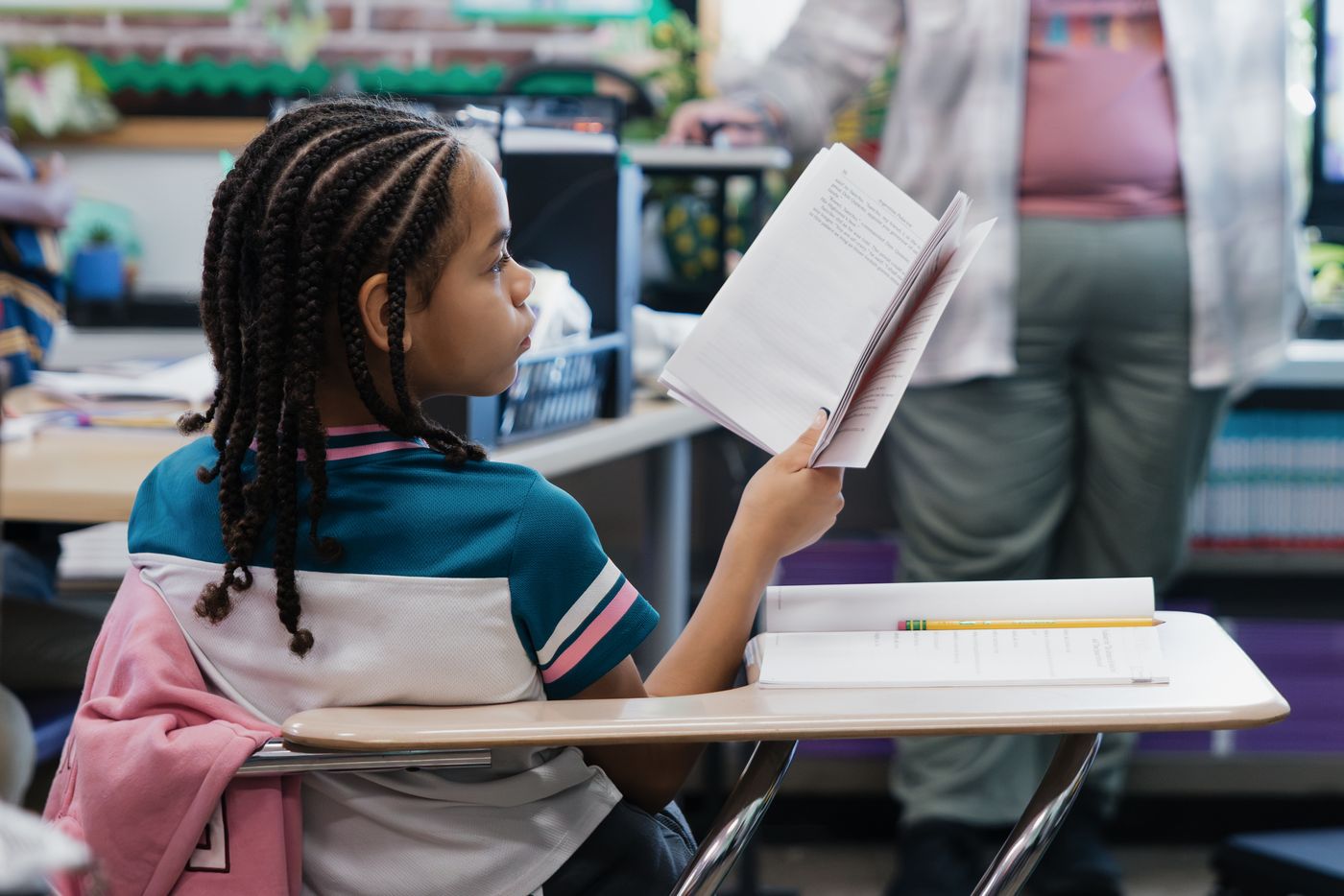 A student holds up a book, reading along with the class.