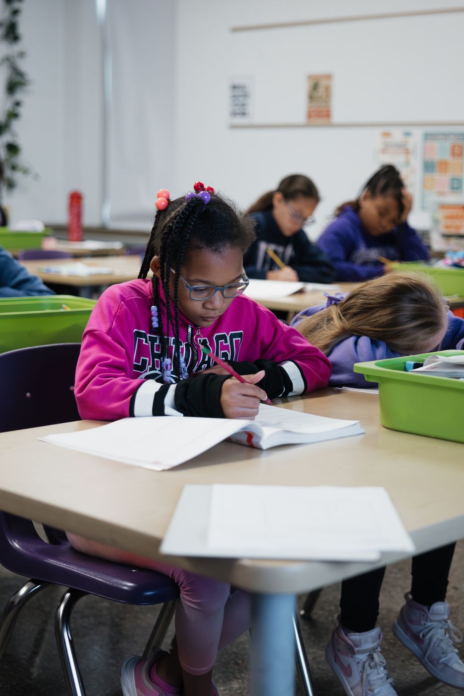 A student writes in a workbook at her desk.