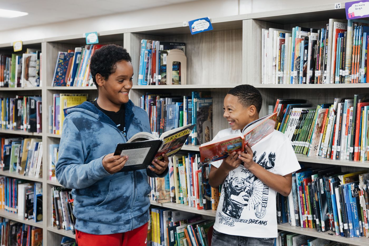 Two students laugh over the books they have picked in the library.