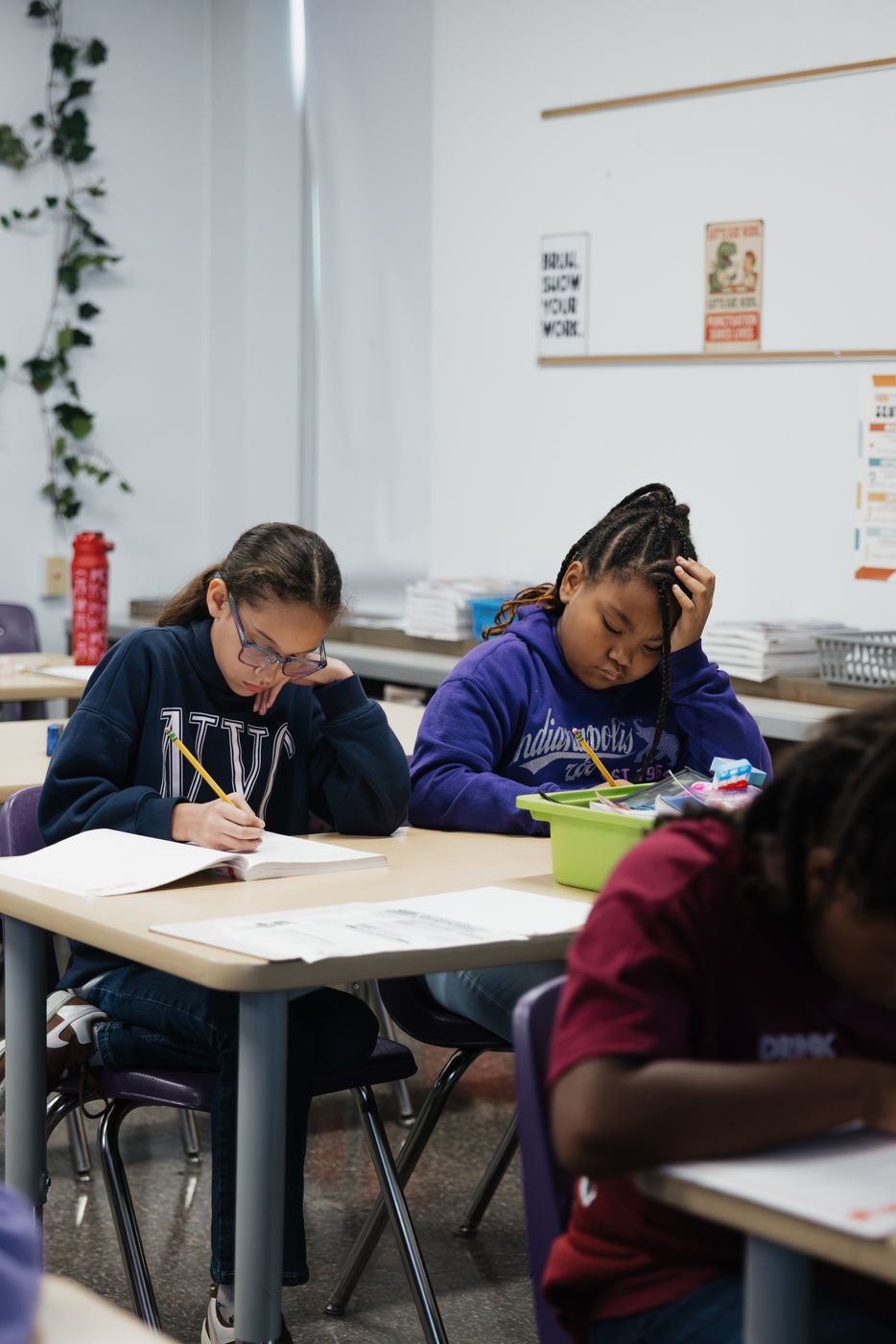Two students work side by side on a writing assignment.