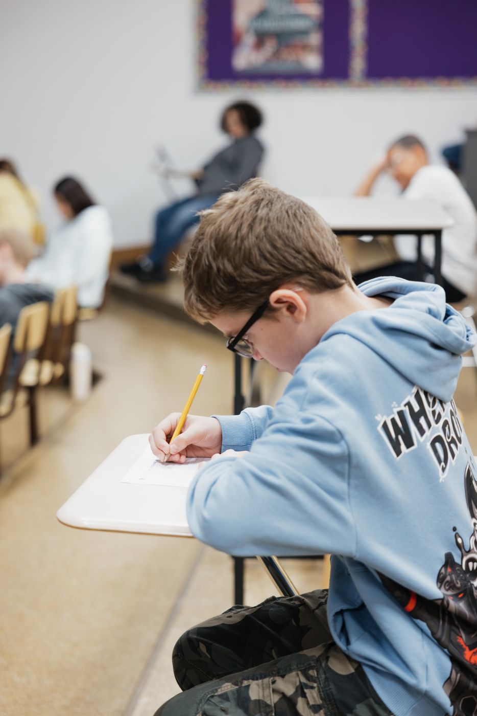 A student leans in over his paper, working steadily.