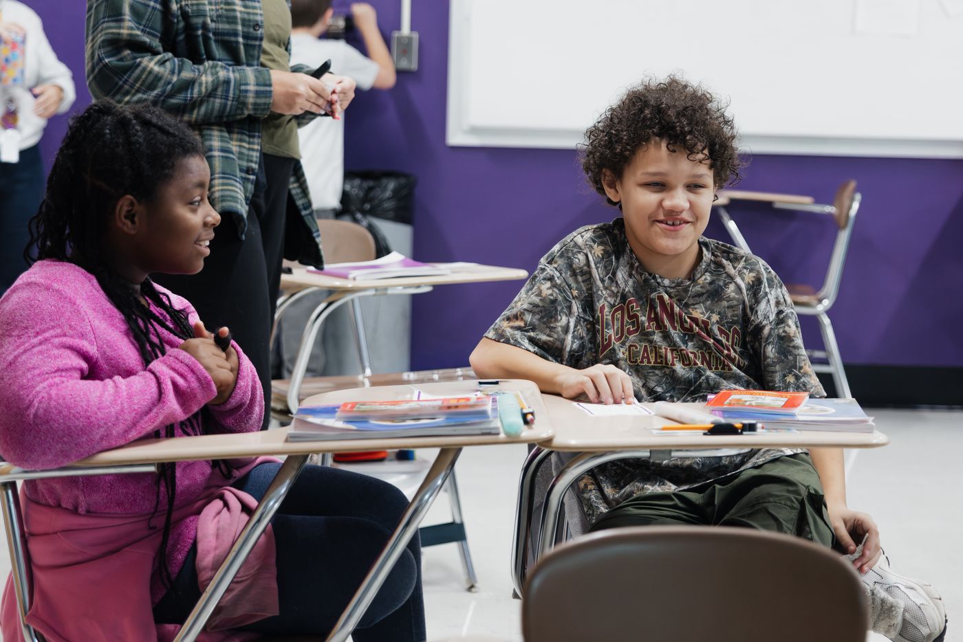 Two students turn to talk at their desks.